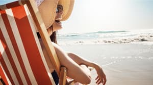 A woman sitting on a beach chair enjoying her beach vacation.
