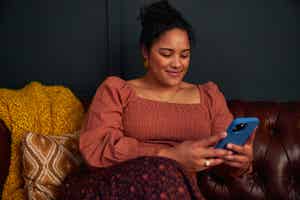 Woman sitting on a sofa holding a blue phone