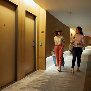 2 women walking down a hotel corridor with bags