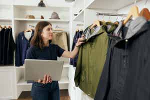Woman browsing clothes while holding laptop
