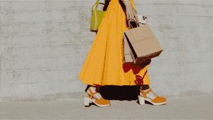The bottom half of a woman walking outside after shopping.