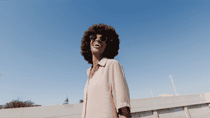 A woman smiling with a view of the sky behind her.