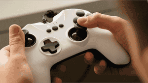 A hand holding a white video game controller.