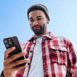 Person outdoors holding their smartphone and looking at the screen