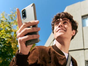 Giovane uomo in piedi all'aperto che tiene un telefono.