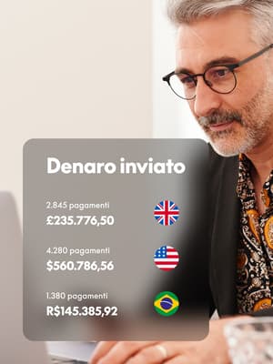 Un uomo lavora al suo laptop con sovrapposizione di una schermata Denaro inviato che mostra valute di UE, USA e Brasile.