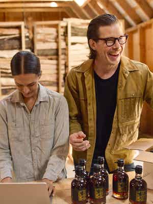 Due persone in un laboratorio che impacchettano bottiglie in una scatola.