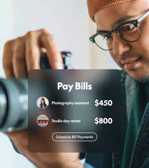 Photographer holding camera with overlay reading “Pay Bills” and a “Schedule Bill Payments” button for a $450 assistant and $800 studio rental