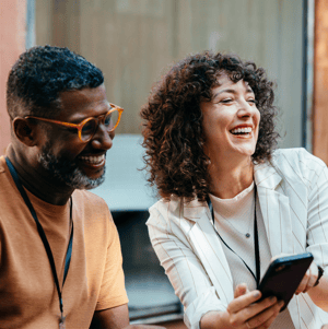 Two people laughing together, one holding a phone