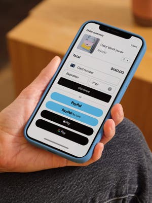 Person holding mobile phone showing checkout screen with payment options including debit/credit card, PayPal, Pay in 4, and Apple Pay