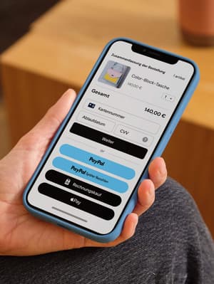 Eine Person hält ein Mobiltelefon in der Hand, das den Kassenbildschirm mit Zahlungsoptionen wie Debit-/Kreditkarte, PayPal, Pay Later und Apple Pay anzeigt.