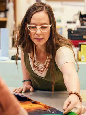 Une femme dans un atelier étirant une grande pièce de tissu sur le comptoir