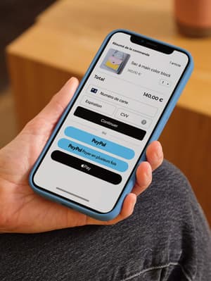 Texte alternatif de l'image : Personne tenant un téléphone portable affichant un écran de commande avec des options de paiement incluant carte de débit/crédit, PayPal, Paiement en 4X et Apple Pay
