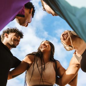A group of friends is standing in a circle smiling down at us.