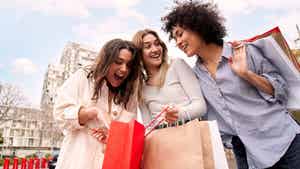 Three women smiling and holding shopping bags