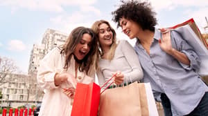 Three women smiling and holding shopping bags