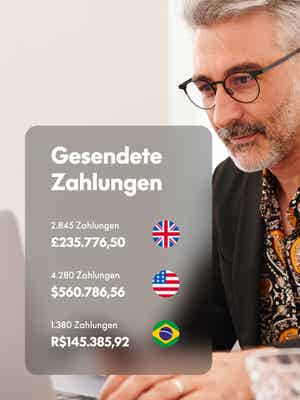 Person, die am Laptop arbeitet und ein Telefon mit einem Overlay von Geld in verschiedenen Währungen hält