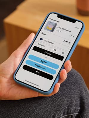Person holding mobile phone showing checkout screen with payment options including debit/credit card, PayPal, Pay Later, and Apple Pay