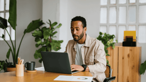 Man working on a laptop at a desk in a home office.