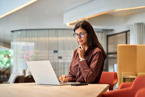 A professional woman reviews information on a laptop in a modern office environment.