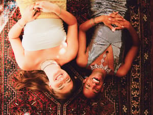 Two friends laughing together while relaxing on a colorful rug