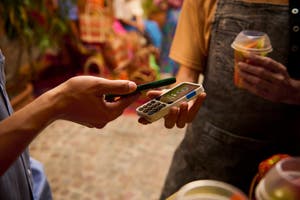Person uses PayPal World to tap to pay at a local market.