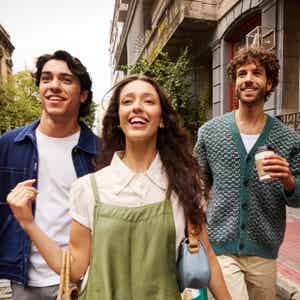 Three friends walking outdoors on a city street, smiling and enjoying themselves
