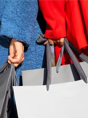 Close-up of two people holding shopping bags